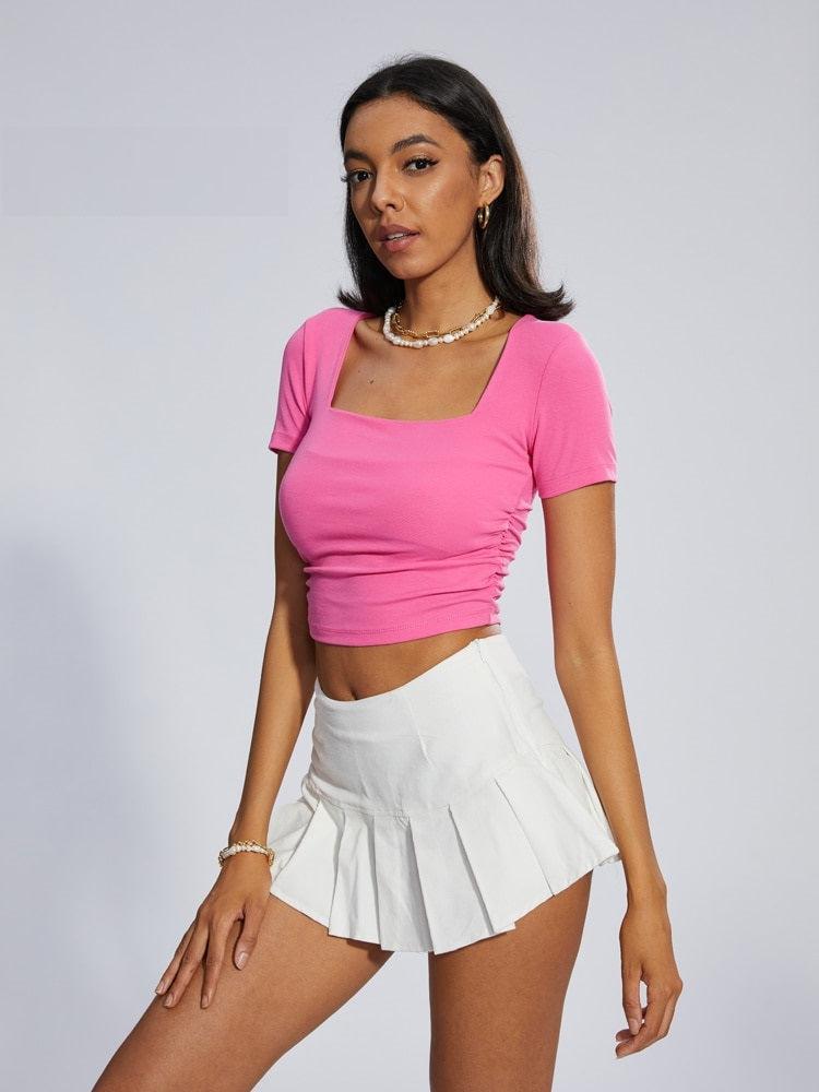 a girl wearing a pink barbie cop top and a white barbie pleated skirt