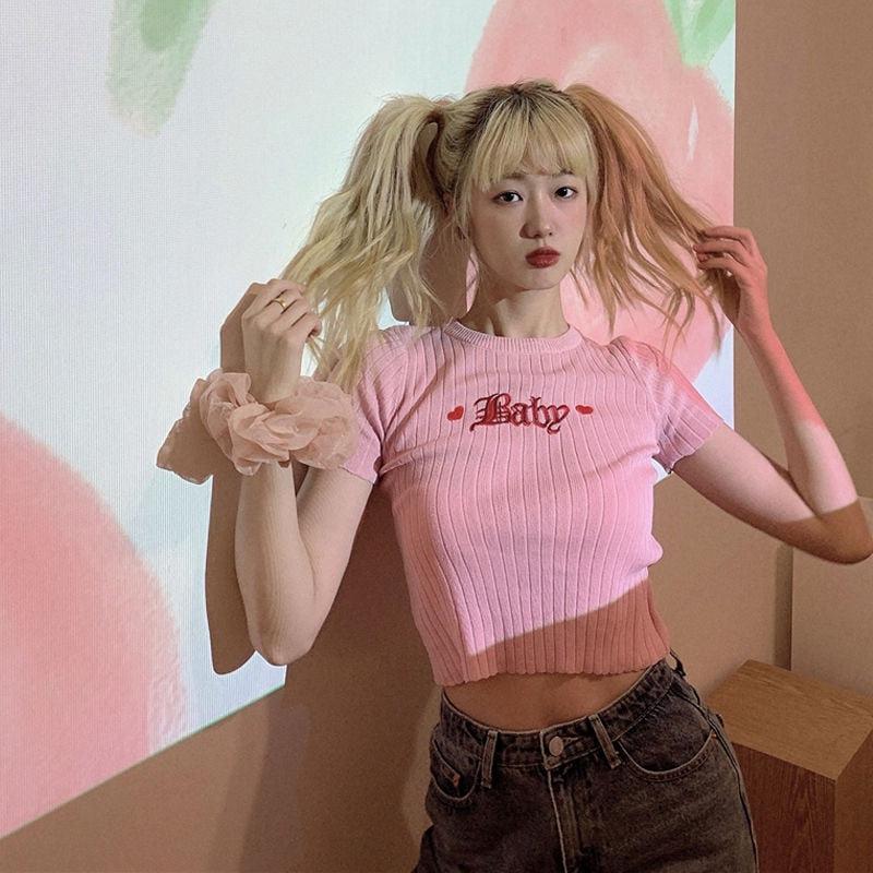 a blonde girl wearing a pink barbie embroidered cop top