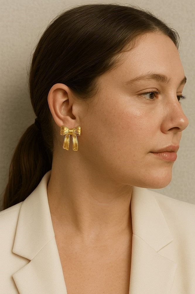 Close-up of a woman wearing a gold bow-shaped earring