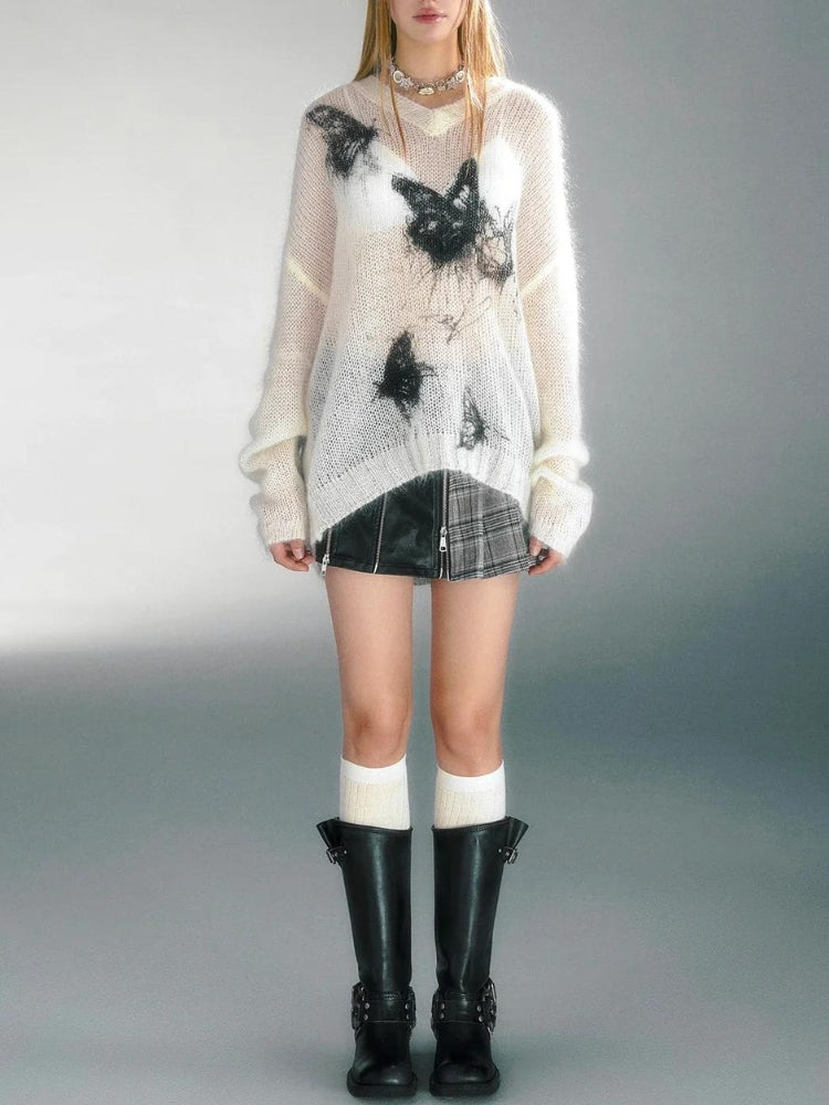 Model wearing a white crochet butterfly sweater with black butterfly patterns, paired with a plaid mini skirt, knee-high socks, and black boots, showcasing a grunge-inspired fall aesthetic outfit.