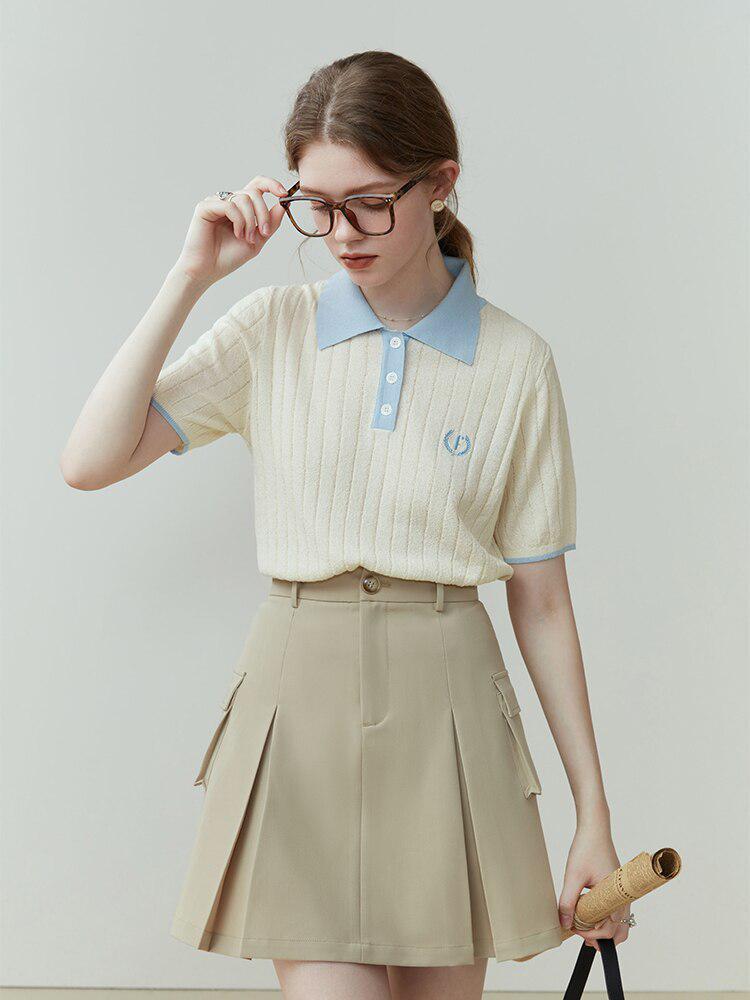 a girl is wearing a college style short sleeve sweater and a beige pleated skirt