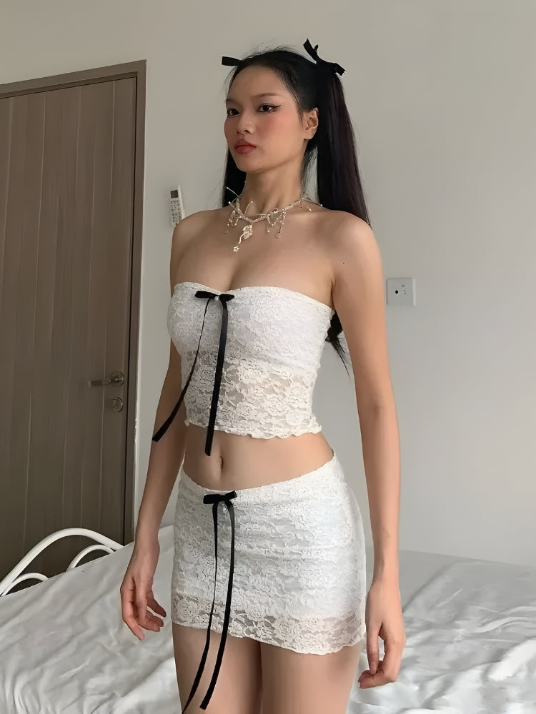 a girl wearing a white coquette aesthetic bow lace two piece set with black bow details and she is wearing a golden necklace