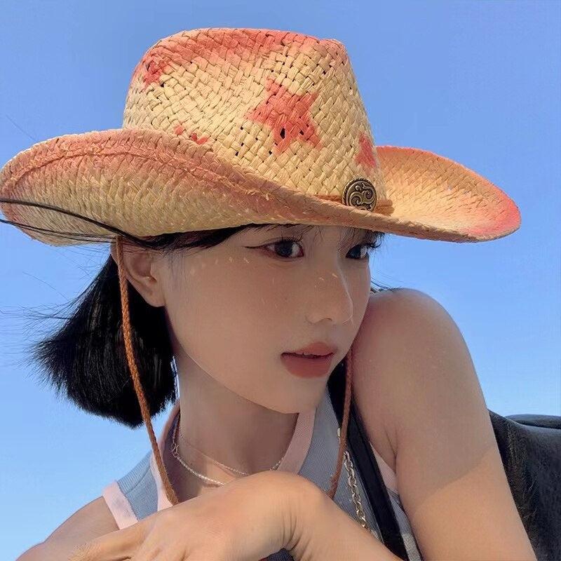 a coastal cowgirl is wearing a cowgirl adjustable woven straw hat and there are pink stars on the hat
