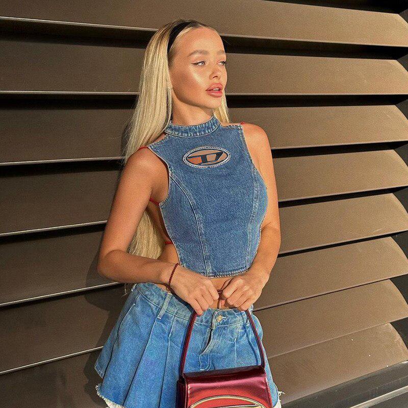a blonde girl wearing a disco cowgirl denim halter corset top and a denim plaid skirt and she is holding her mini bag