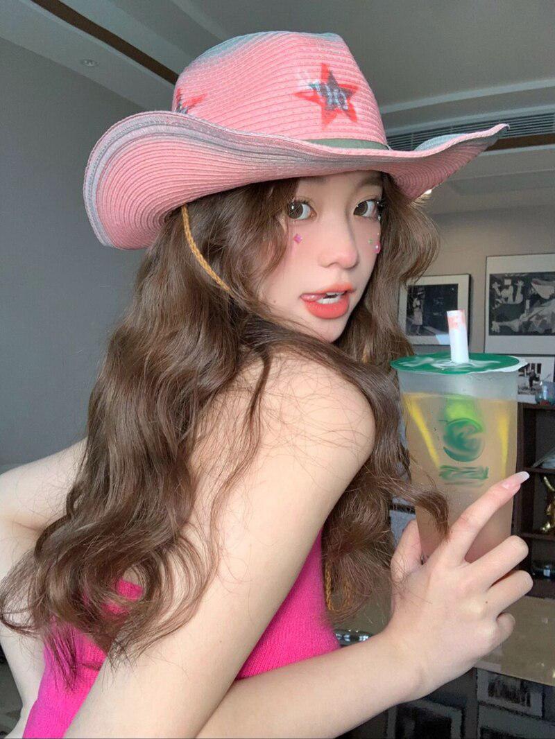 a cute girl wearing a pink disco cowgirl adjustable star printed hat and she is holding her drink