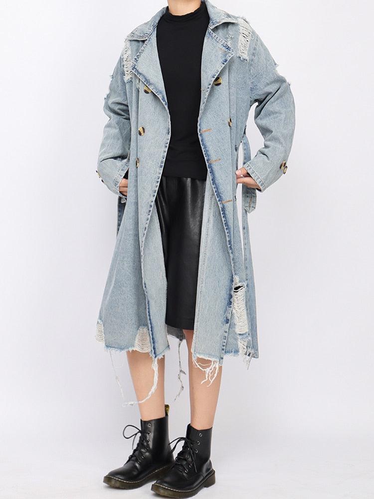 a girl wearing a blue distressed denim trench coat, a basic top, a faux leather skirt and combat boots