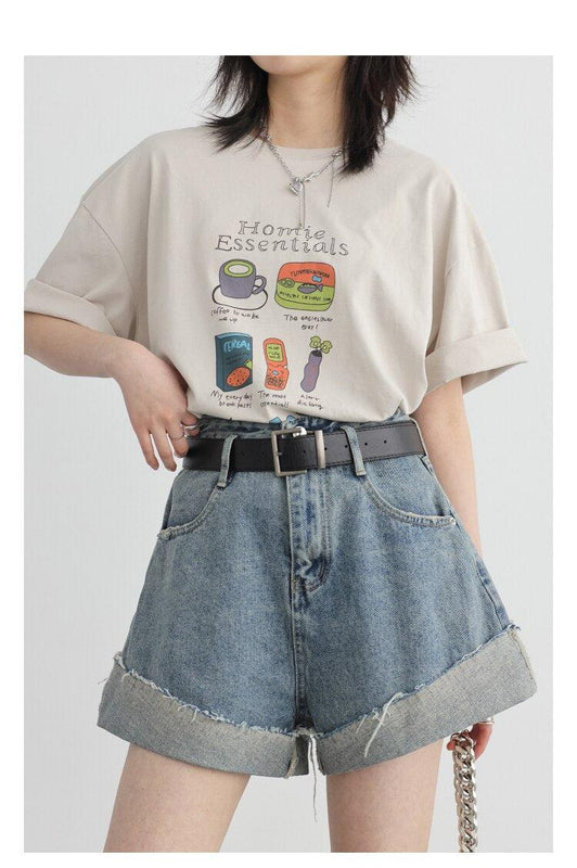 une fille porte un short en jean déchiré et fendu, une ceinture noire, un collier argenté et un tee-shirt avec des imprimés d'articles ménagers