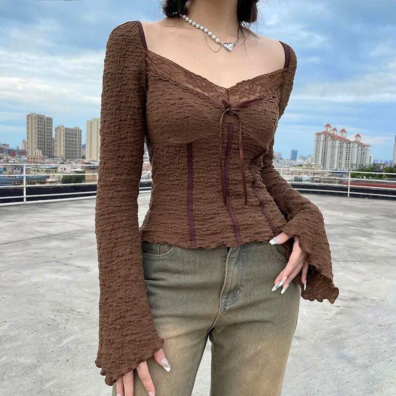 Una niña lleva una blusa fruncida con detalles de encaje de hadas, un collar de perlas y jeans.