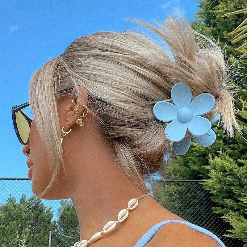 ein blondes Mädchen, das eine ästhetische Haarspange in Form einer blauen Blume trägt