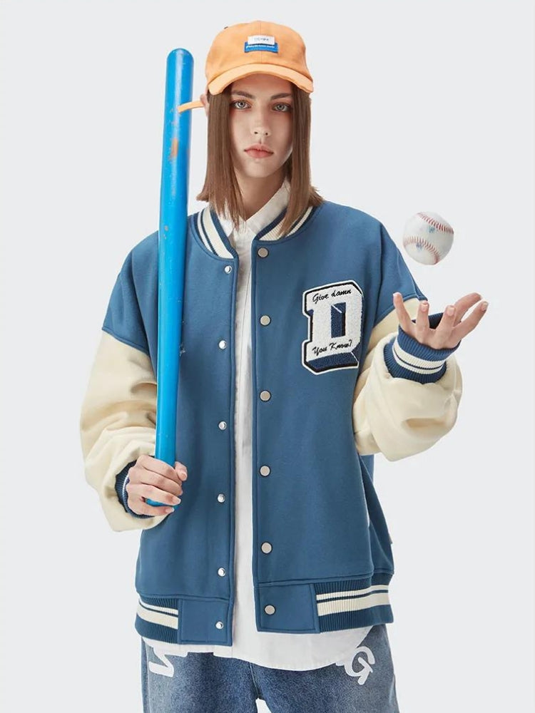 a girl is wearing an i don't give a damn baseball vasity jacket in blue and white and an orange hat and she is holding a baseball bat and a ball