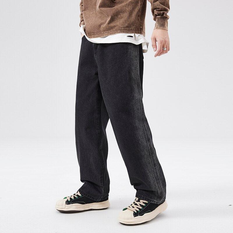 Un niño suave que viste jeans casuales de estética azul y zapatillas Converse y una camisa negra de manga larga.