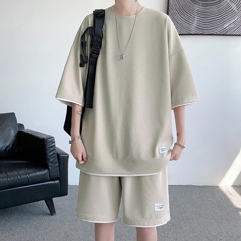 Un niño suave que viste un conjunto de dos piezas de sudadera y pantalones cortos deportivos de estética beige.