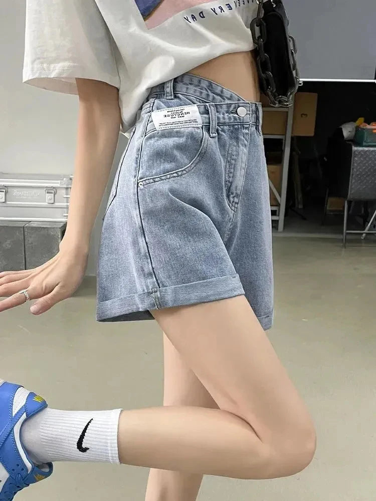 a girl is wearing light blue Y2K asymmetric waist denim shorts with high waist and wide leg fit