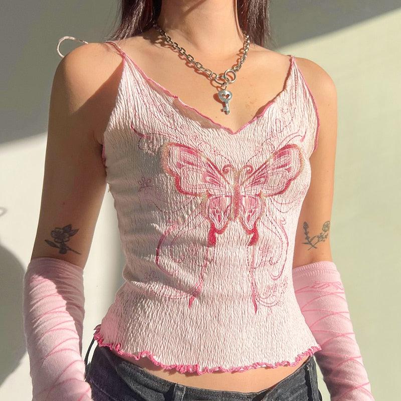 a girl is wearing a y2k butterfly printed pink crop top and a silver necklace with a key on